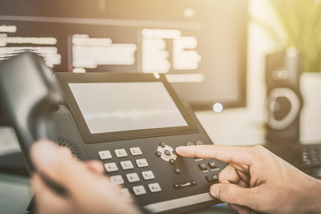 A finger pressing the buttons of a VoIP display.