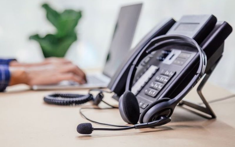 An older VoIP phone with a wired headset resting nearby.