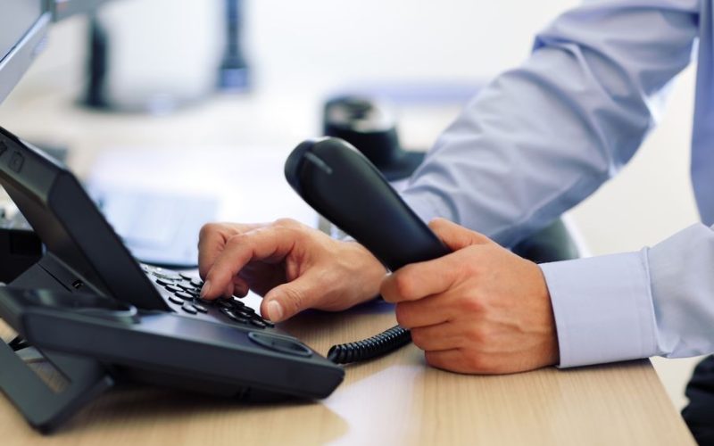 A man's hands as he dials in a number on a VoIP phone.