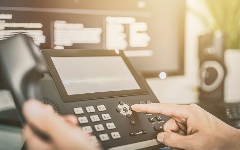 A finger pressing the buttons of a VoIP display.